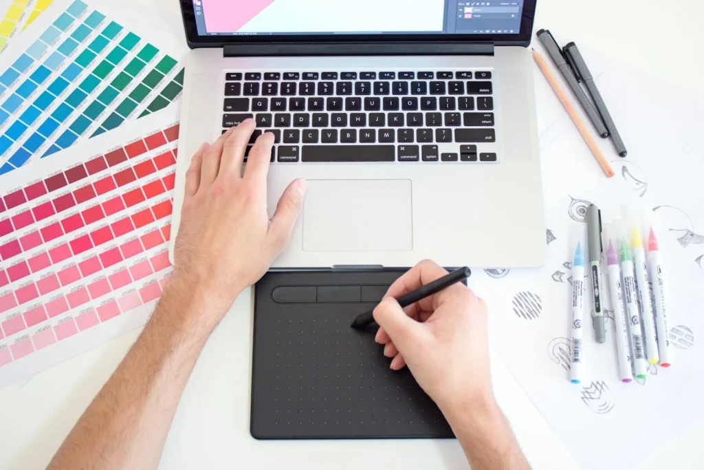 Graphiste dessinant sur une tablette graphique à côté d’un ordinateur