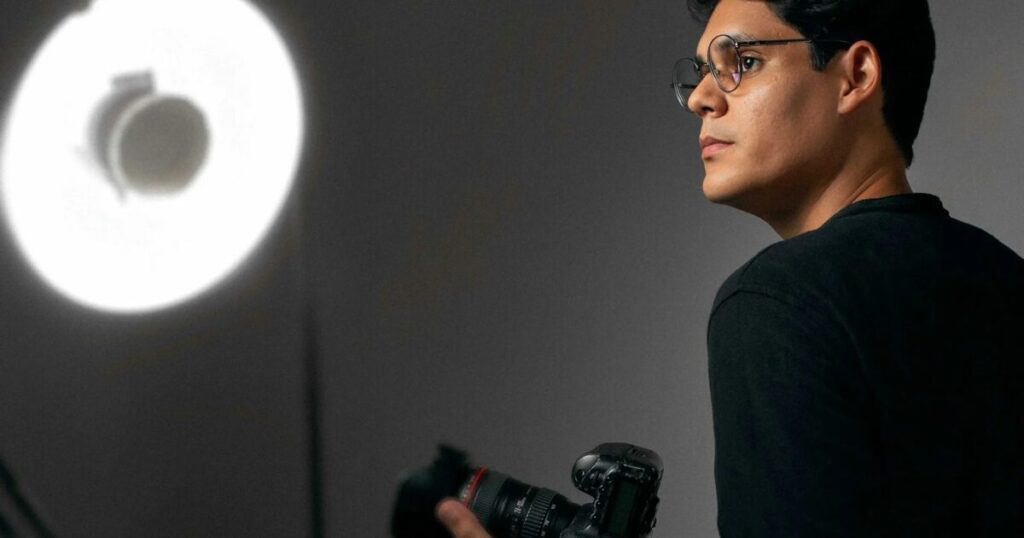 Photographe tenant son appareil devant une source de lumière