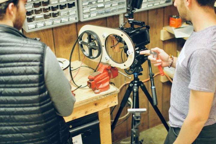 Tournage dans un atelier, caméra sur trépied face à un artisan