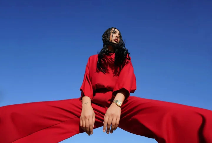 Modèle en tenue rouge posée devant un fond coloré