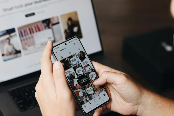 Smartphone tenu devant un ordinateur portable