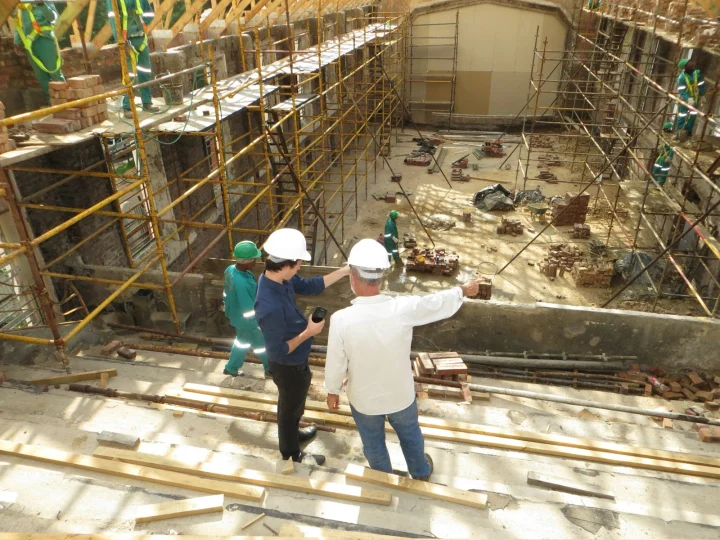 Deux hommes en casque de chantier désignant un bâtiment
